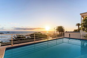 Ein Pool mit Blick auf den Ozean bei Sonnenuntergang.