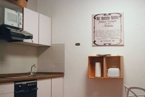 Eine Küche mit weißen Schränken, einer Mikrowelle und einem Holzboden mit einer Küchenpapierrolle.