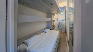 Ein Schlafzimmer mit einem Etagenbett, einem kleinen Nachttisch und einem an der Wand befestigten Regal.