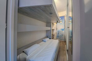 Ein Schlafzimmer mit einem Etagenbett, einem kleinen Nachttisch und einem an der Wand befestigten Regal.