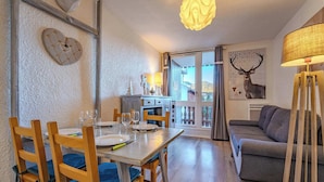 Ein Essbereich mit einem Holztisch, gedeckt für vier Personen, einer Couch und einer Lampe.