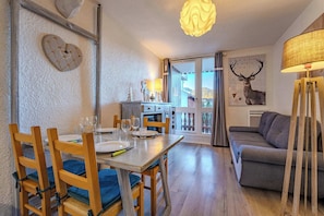 Ein Essbereich mit einem Holztisch, gedeckt für vier Personen, einer Couch und einer Lampe.