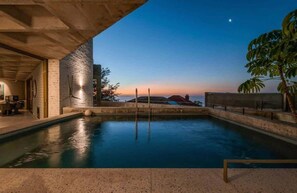 Ein Pool mit Blick auf einen Sonnenuntergang, ein Betongebäude und ein Blumentopf.