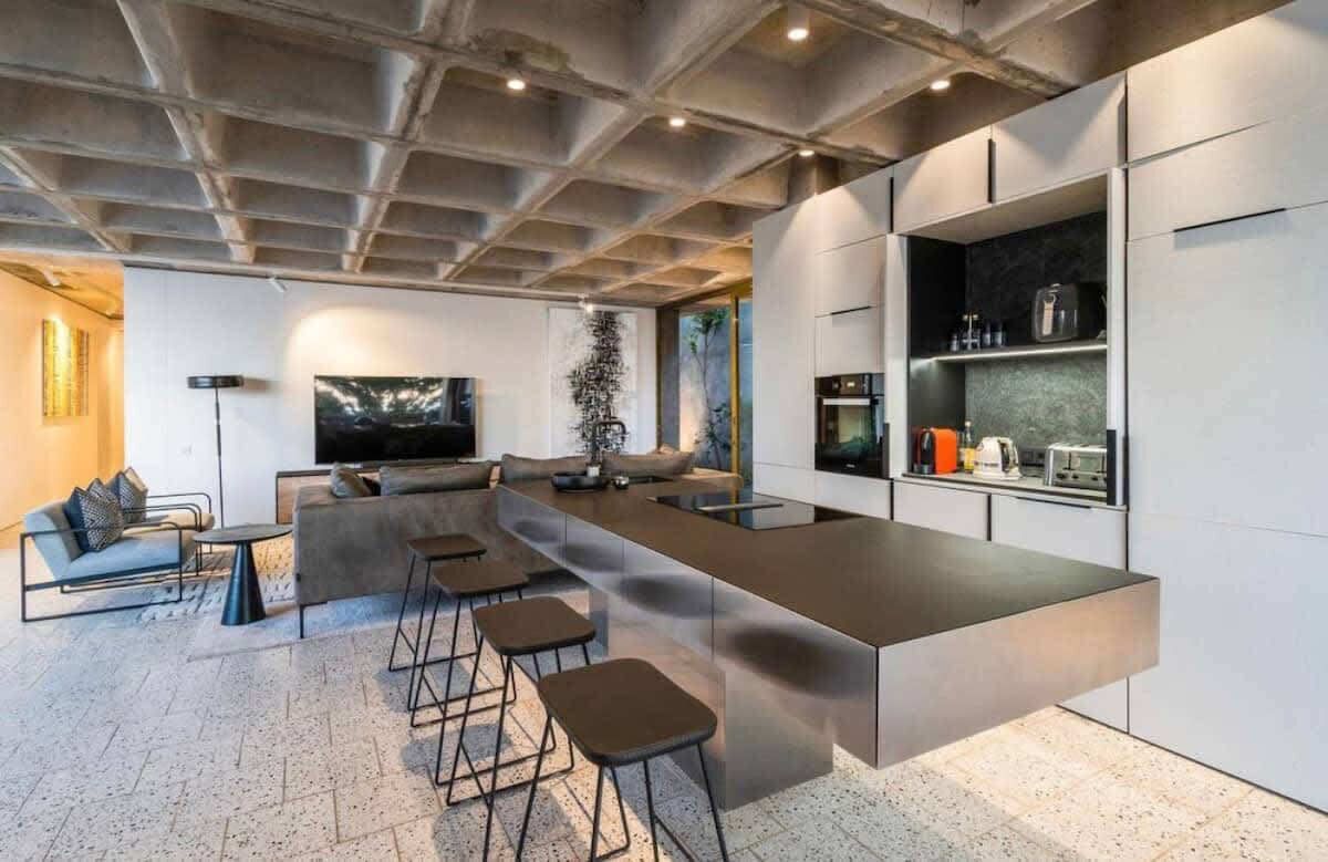 A modern kitchen with a long island counter, bar stools, and built-in appliances.