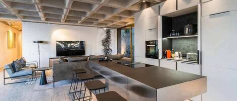 A modern kitchen with a long island counter, bar stools, and built-in appliances.