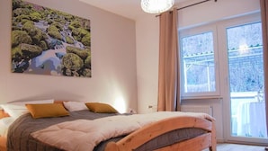 Una camera da letto con un letto in legno, un'ampia finestra vista alberi e un quadro appeso al muro.