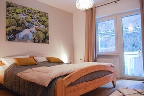 Ein Schlafzimmer mit einem hölzernen Bett, einem großen Fenster mit Blick auf Bäume und einem Gemälde an der Wand.