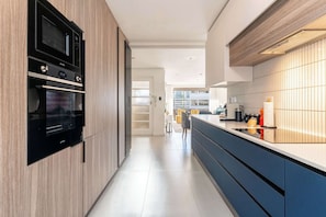 A modern kitchen with built-in appliances, a long counter, and a view into the dining area. - Modern Apt, Views, Perfect Location - Bantry Alanda (Cape Town)