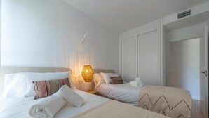 Ein Hotelzimmer mit zwei Betten, einer Nachttischlampe, einem Kleiderschrank und einer Tür.