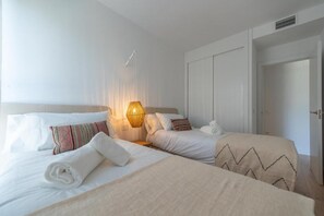 Ein Hotelzimmer mit zwei Betten, einer Nachttischlampe, einem Kleiderschrank und einer Tür.