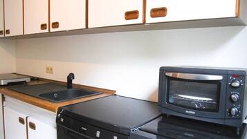 A compact kitchenette with a black toaster oven, a sink, and a dishwasher.