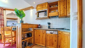 A kitchen with wooden cabinets, a microwave, a dishwasher, and a potted plant. - Alpine Stay w/ Private Ski Views (Les Belleville)