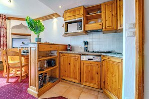 Eine Küche mit Holzschränken, einer Mikrowelle, einem Geschirrspüler und einem Blumentopf.
