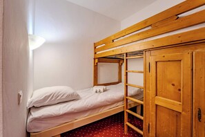 Ein Stockbett mit Holzleiter und einem Kleiderschrank.