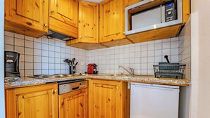 Een keuken met houten kastjes, een magnetron, een koffiezetapparaat en een vaatwasser.