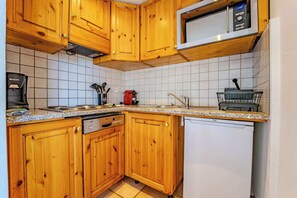 A kitchen with wooden cabinets, a microwave, a coffee maker, and a dishwasher. - Mountain-View with Ski-In ski Out Stay (Les Belleville)