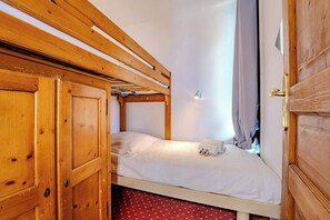 A single bed with a wooden headboard, a white mattress, and a small bedside table with a lamp. - Mountain-View with Ski-In ski Out Stay (Les Belleville)