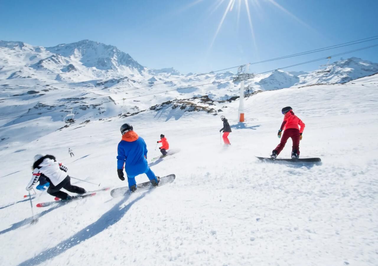 Ein verschneiter Skipisten mit Skifahrern und Snowboardern.