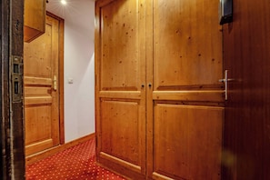 A hallway with wooden double doors, a red patterned carpet, and a light fixture on the ceiling. - Mountain-View with Ski-In ski Out Stay (Les Belleville)
