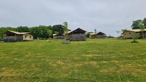 A grassy field with several small, single-story buildings with sloped roofs, likely cabins or cottages.