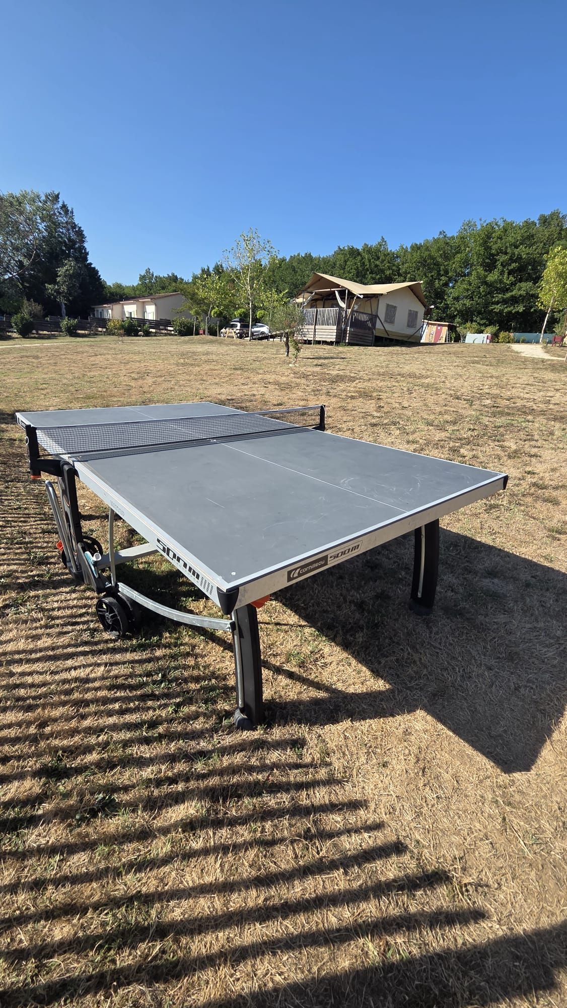 Une table de ping-pong portable installée en plein air, sous un ciel dégagé.