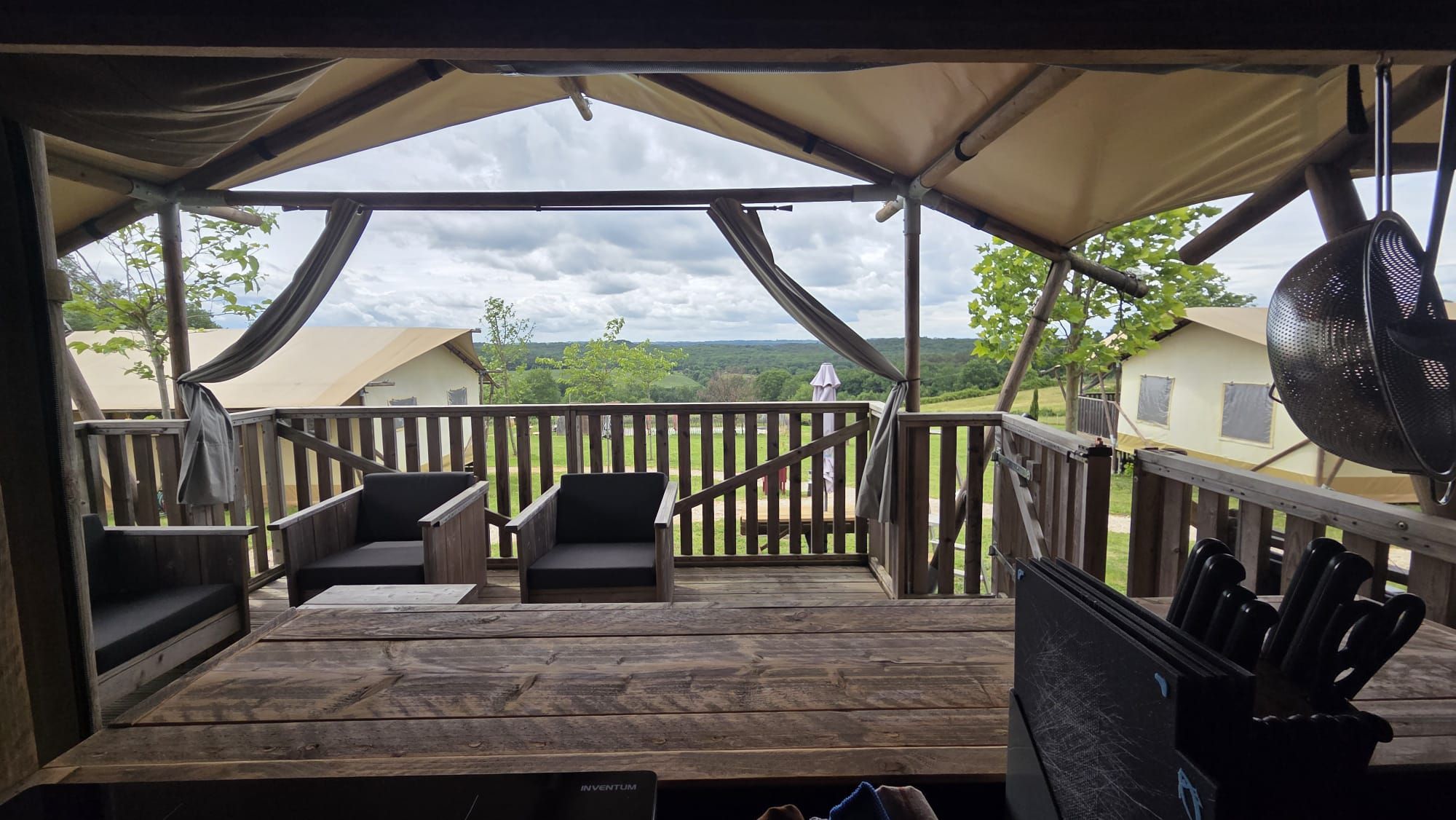 A covered outdoor deck with wooden railings and two chairs.