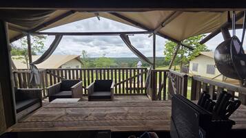A covered outdoor deck with wooden railings and two chairs.