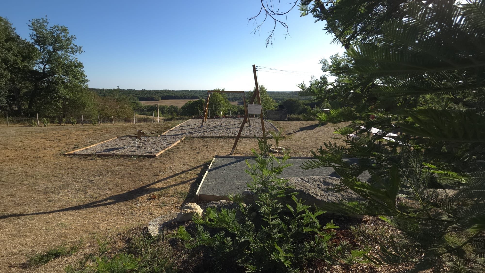 An outdoor area with a paved path, a signboard, and a fenced field.