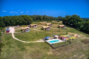 An aerial view of a campsite with multiple tents, a swimming pool, and a parking area.