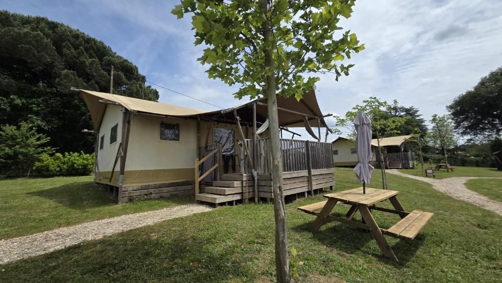 Un terrain de camping équipé d’une structure abritant des tentes, d’une table de pique-nique et d’un escalier menant à une terrasse.
