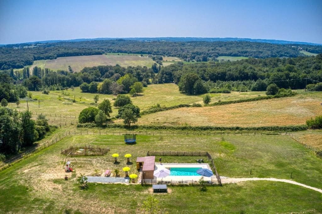A rural property with a swimming pool, fenced garden, and a clear view of the surrounding countryside.