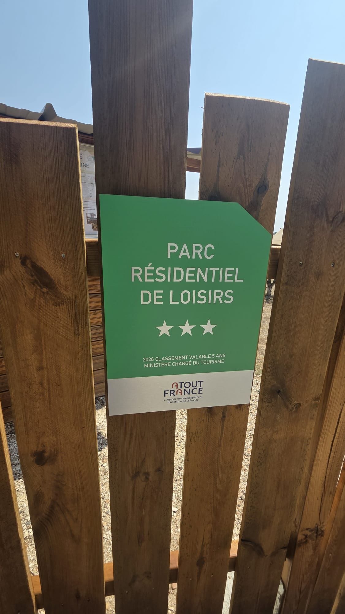Una valla de madera con un letrero que dice 'PARC RÉSIDENTIEL DE LOISIRS' y menciona una calificación de 2026 por el Ministerio de Turismo.