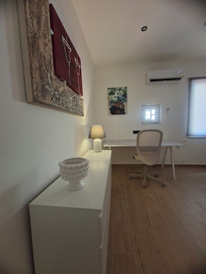 Ein moderner Arbeitsraum mit Schreibtisch, Stuhl und einem Bild an der Wand.