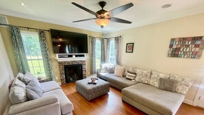 Ein Wohnzimmer mit Kamin, zwei Sofas, einem Couchtisch und einem Deckenventilator.