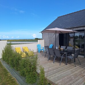 An outdoor patio with a table and chairs, a wooden deck, and a view of the landscape. - Holiday Home in Brittany With Sea View (Cleder)