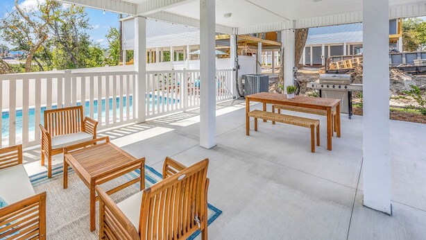 A covered outdoor area with a pool, wooden furniture, and a barbecue grill. - Rosemary Villa, Heated Saltwater Pool, Volleyball Court, Golf Cart, Main ST (North Myrtle Beach)