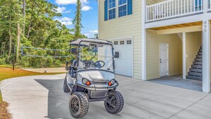 A golf cart parked in a driveway with a house in the background. - Rosemary Villa, Heated Saltwater Pool, Volleyball Court, Golf Cart, Main ST (North Myrtle Beach)