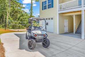 A golf cart parked in a driveway with a house in the background. - Rosemary Villa, Heated Saltwater Pool, Volleyball Court, Golf Cart, Main ST (North Myrtle Beach)