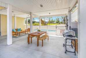 A covered patio with a wooden table and chairs, a grill, and a view of a swimming pool. - Rosemary Villa, Heated Saltwater Pool, Volleyball Court, Golf Cart, Main ST (North Myrtle Beach)