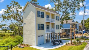 A two-story building with a balcony, a garage, and a golf cart in front. - Rosemary Villa, Heated Saltwater Pool, Volleyball Court, Golf Cart, Main ST (North Myrtle Beach)