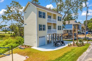 A two-story building with a balcony, a garage, and a golf cart in front. - Rosemary Villa, Heated Saltwater Pool, Volleyball Court, Golf Cart, Main ST (North Myrtle Beach)