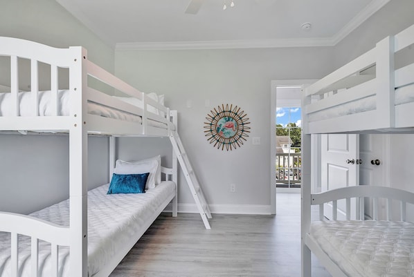 Quarto com beliche, uma peça decorativa na parede e vista através de uma porta aberta.