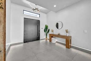 Een modern interieur met een gesloten deur, een console tafel met decoratieve objecten en een ronde spiegel aan de muur.