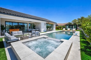 Een modern huis met een zwembad, terras en een jacuzzi.