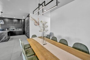 A modern dining area with a wooden table, green upholstered chairs, and a vase with flowers. - The signature Luxury Las Vegas Getaway (Las Vegas)