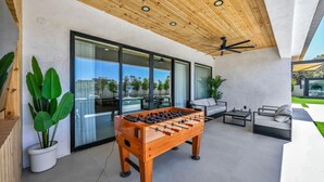 Ein moderner Außenbereich mit Tischfußball, Sitzgelegenheiten und Blick auf einen Pool.