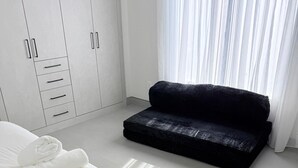 Ein Schlafzimmer mit einem Bett, einem schwarzen Sofa, einem Kleiderschrank und einem Fenster mit Vorhängen.