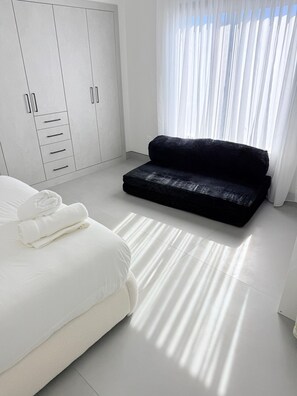A bedroom with a bed, a black sofa, a wardrobe, and a window with curtains. - The signature Luxury Las Vegas Getaway (Las Vegas)