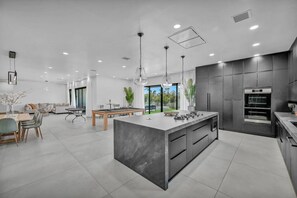 A modern kitchen with a central island, built-in appliances, and a dining area with a pool table. - The signature Luxury Las Vegas Getaway (Las Vegas)
