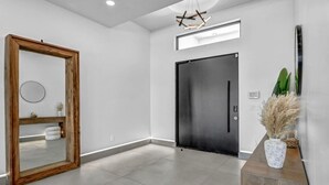 Ein modernes Interieur mit einem großen Spiegel, einer schwarzen Tür und einer Holzkonsole mit einer Vase.